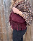 Person wearing a leopard print top & burgundy suede fringed shoulder bag for autumn winter