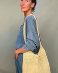 Woman holding a yellow woven bag against a plain background