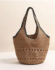 Woven beige and black raffia handbag with black trim on a light background.