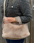 woman holding a beige shoulder bag with a leopard print jacket