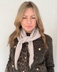 woman wearing a leopard print jacket with a beige triangle scarf