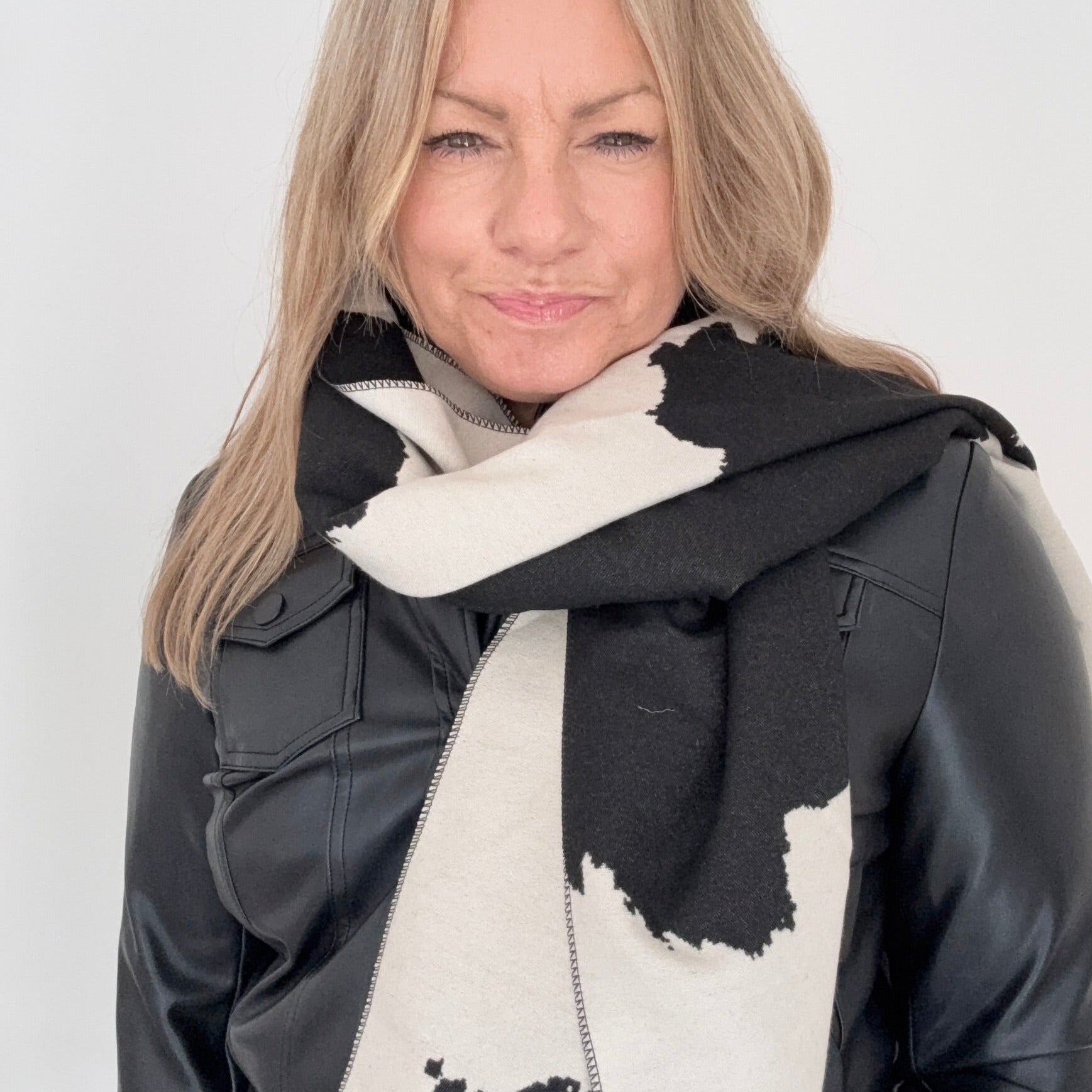 Woman wearing a black and white cow print patterned blanket scarf for Autumn Winter layering