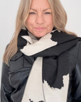Woman wearing a black and white cow print patterned blanket scarf for Autumn Winter layering