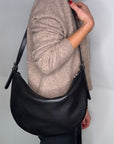 lady holding a black crossbody/ shoulder handbag.