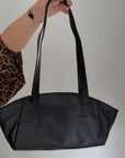 Black leather handbag held by a woman
