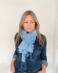 Woman wearing a blue denim jacket and striped blue scarf on a white background