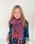 Woman wearing a blue, pink and orange animal print scarf and a denim shirt.