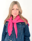 Woman wearing a pink cotton triangle scarf and blue denim jacket on a white background