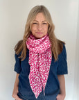 Woman wearing a pink and white leopard print scarf and a blue denim top