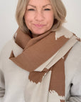 Woman wearing an Autumn Winter camel and cream cow print patterned blanket scarf for layering