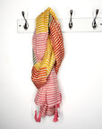 Colorful striped scarf hanging on a white wall with hooks
