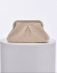Cream knitted cloud clutch bag with a triangle design on a white pedestal against a light gray background