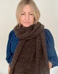 Woman wearing a brown knitted scarf over a blue denim top