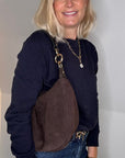 Woman wearing a navy sweater and dark brown suede crossbody / shoulder bag
