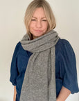 Woman wearing a grey knitted scarf and blue denim top