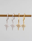 two pairs of sparkly star hoop earrings, one gold and one silver lined up together side by side