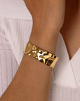 Gold textured cuff bangle bracelet on a wrist with a white background