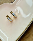 Gold and white earrings on a white dish