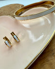 Gold and white earrings on a heart-shaped pink dish