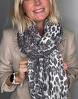 Woman wearing a beige coat and a grey animal print scarf