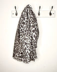 Leopard print scarf hanging on a hook on a white wall