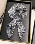 Grey mix animal print scarf in a black frame on a grey surface