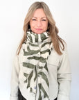 Woman wearing a white coat and khaki zebra print lightweight scarf