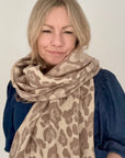 Woman wearing a taupe leopard print scarf on a white background