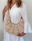 Woman holding a beige croissant textured shoulder handbag