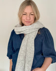 Woman wearing a blue denim shirt and grey knitted blanket scarf