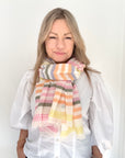 Woman wearing a colorful striped scarf against a white background.