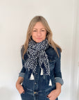 Woman wearing a denim jacket and a Navy and white polka dot scarf on a white background