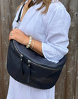 woman wearing a white dress holding a navy blue handbag against a wooden background