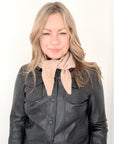 Woman wearing a black leather jacket and pale camel knitted scarf