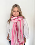 Woman wearing a pink mix patterned scarf against a white background.