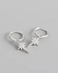 A pair of silver hoop huggies with silver sparkly star charms on a grey background.