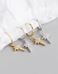 two pairs of silver and gold sparkly star hoop earrings.