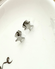Star-shaped silver earrings on a white surface