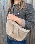 Woman wearing a leopard print jacket holding a stone beige suede crossbody handbag.