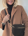 Woman wearing a brown coat with a dark brown crossbody/ waist bag