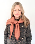 Woman wearing a leopard print jacket and a tan & brown triangle scarf