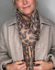 Woman wearing a mixed animal print scarf and beige coat