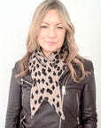 Woman wearing a black leather jacket and a leopard print scarf on a white background
