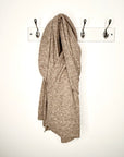 taupe knitted scarf draped over a hook on a white wall