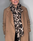 Woman wearing a dark taupe coat, and a taupe leopard print scarf
