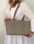 woman holding a beige leather tote handbag