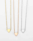 three delicate heart necklaces lined up next to each other.