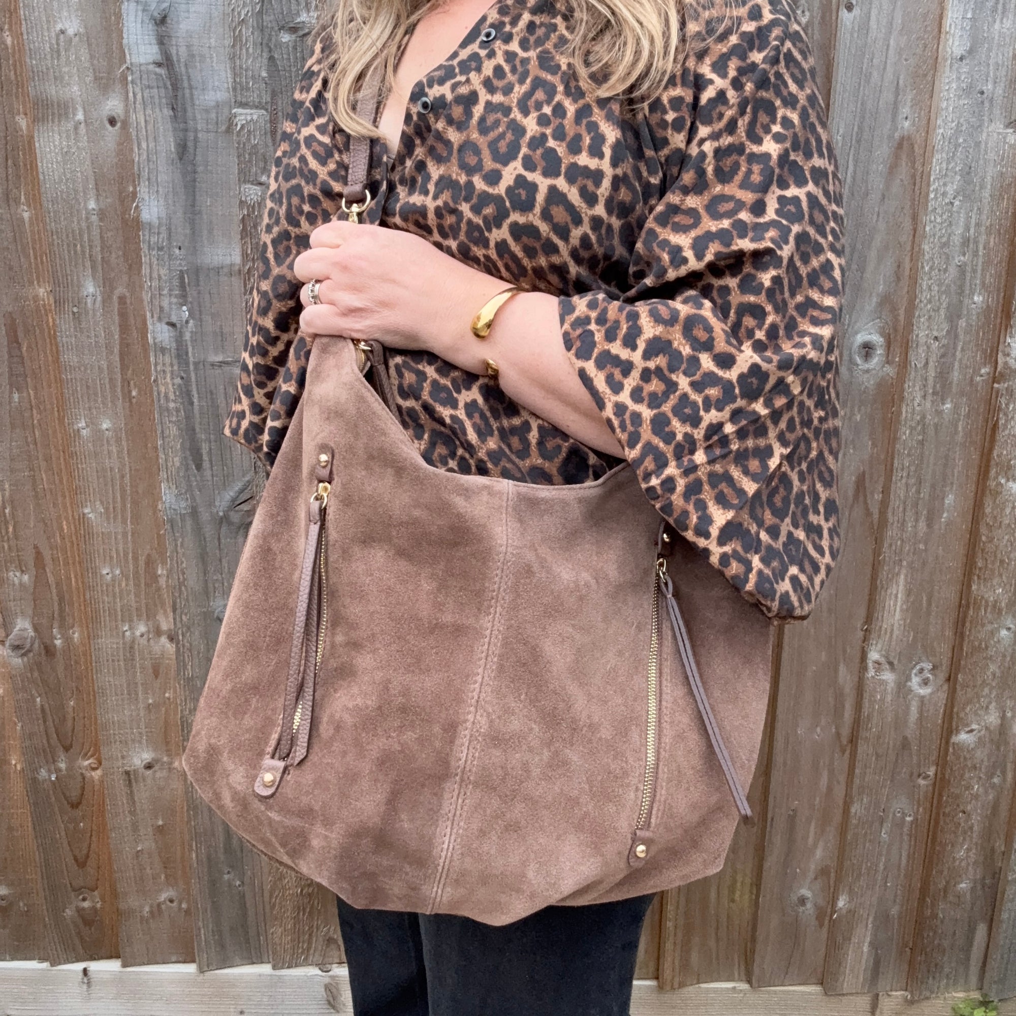 Person wearing a leopard print top and holding a brown suede handbag for autumn winter