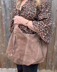 Person wearing a leopard print top and holding a brown suede handbag for autumn winter