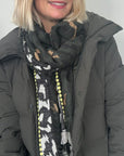 Woman wearing a dark coat and  luxury khaki animal print scarf patterned scarf for autumn winter